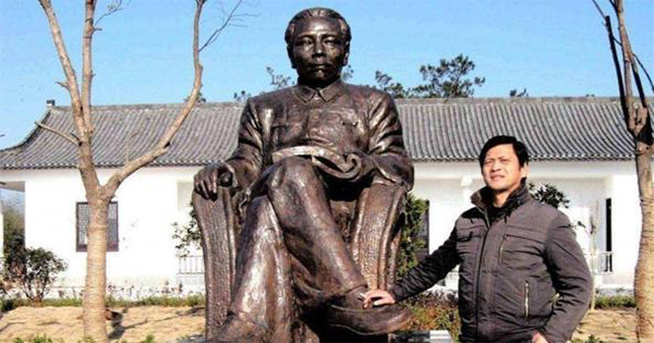 Liu Yongbiao standing next to statue with hand on his foot